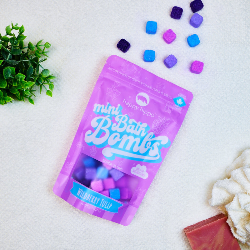 Bag of pink Wildberry Tulip Mini Bath Bombs on a white background with mini bath bombs scattered around it