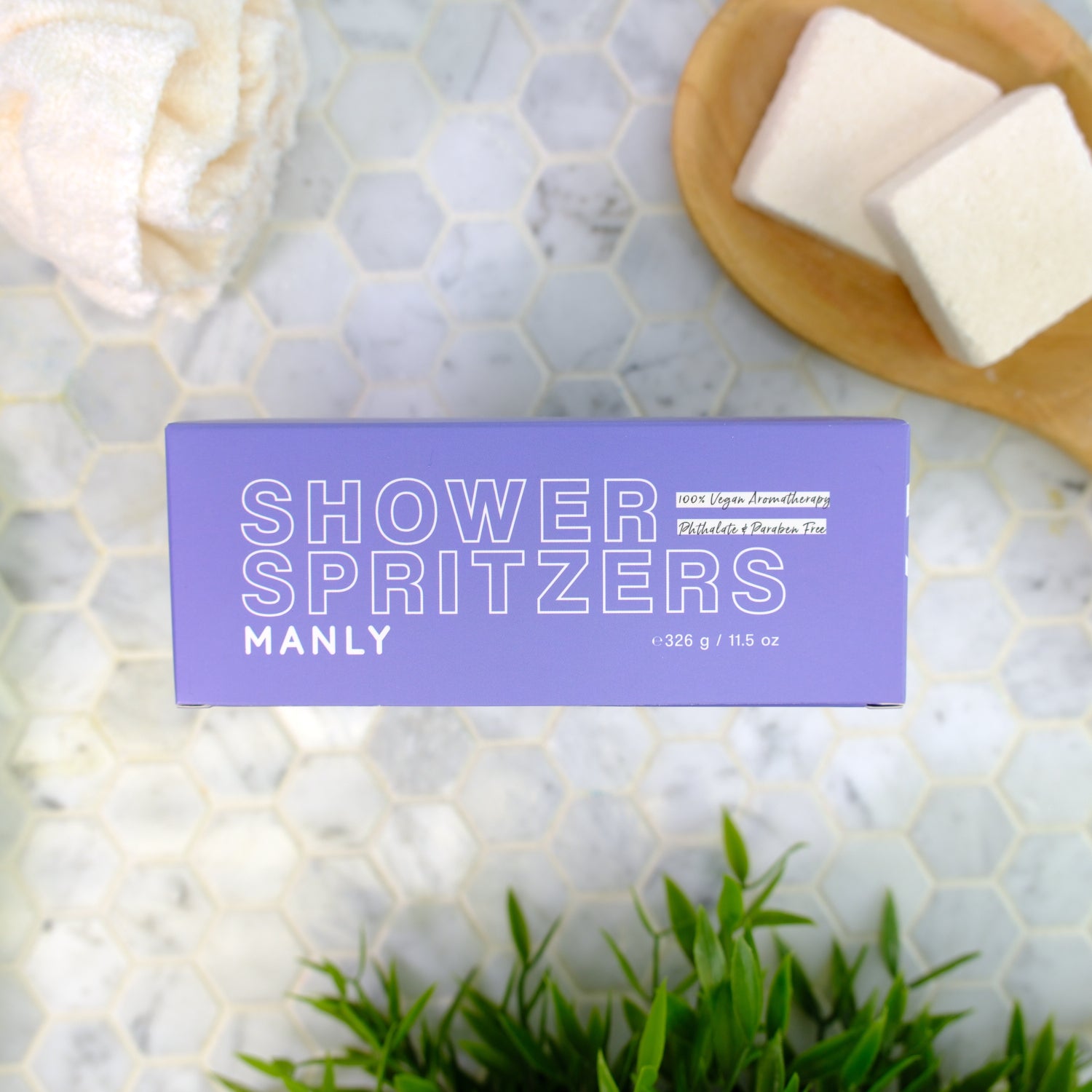 Shower spritzers packaging labeled 'manly' on a marble surface with spritzers and greenery.