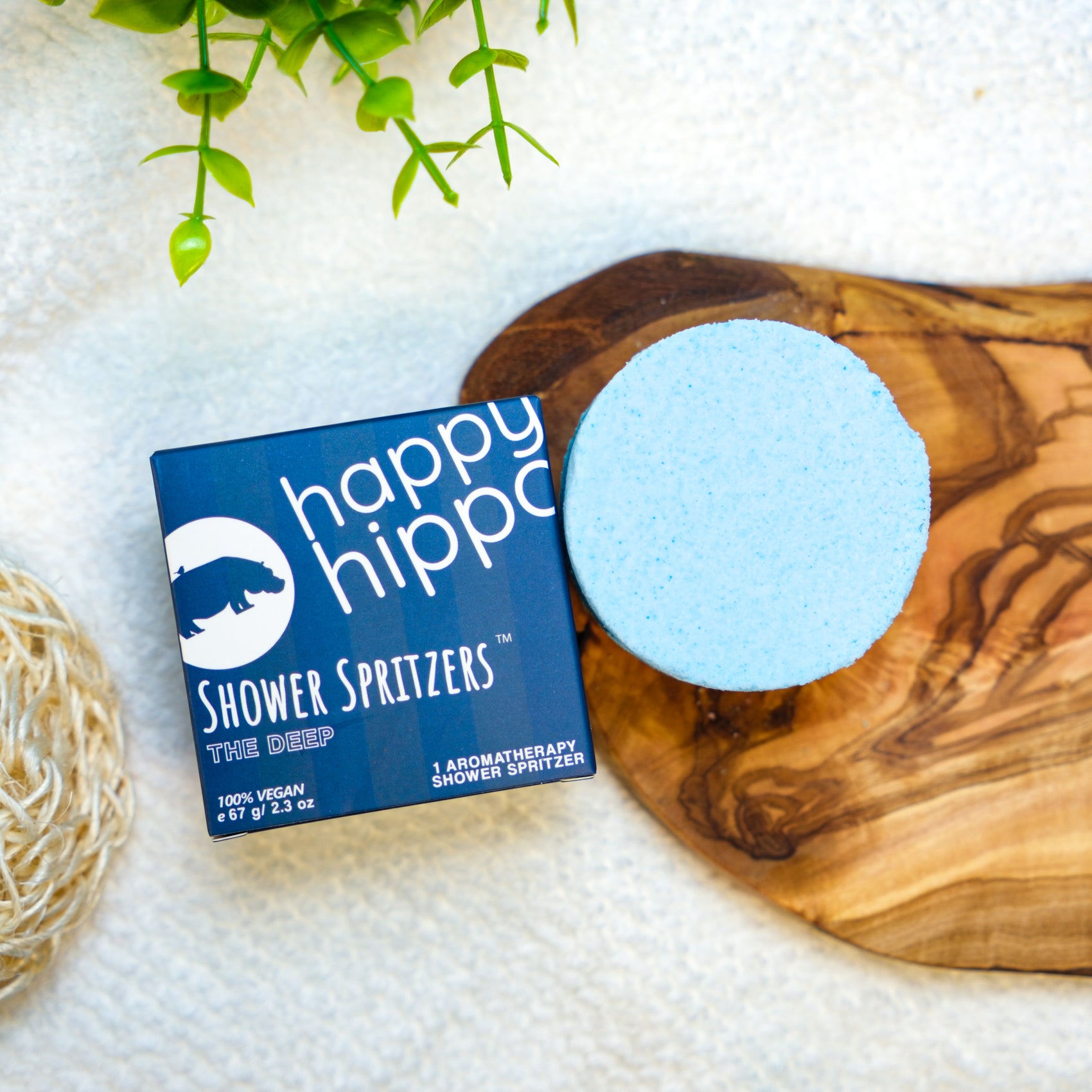Happy Hippo Shower Spritzer packaging with a blue round product on a wooden board.
