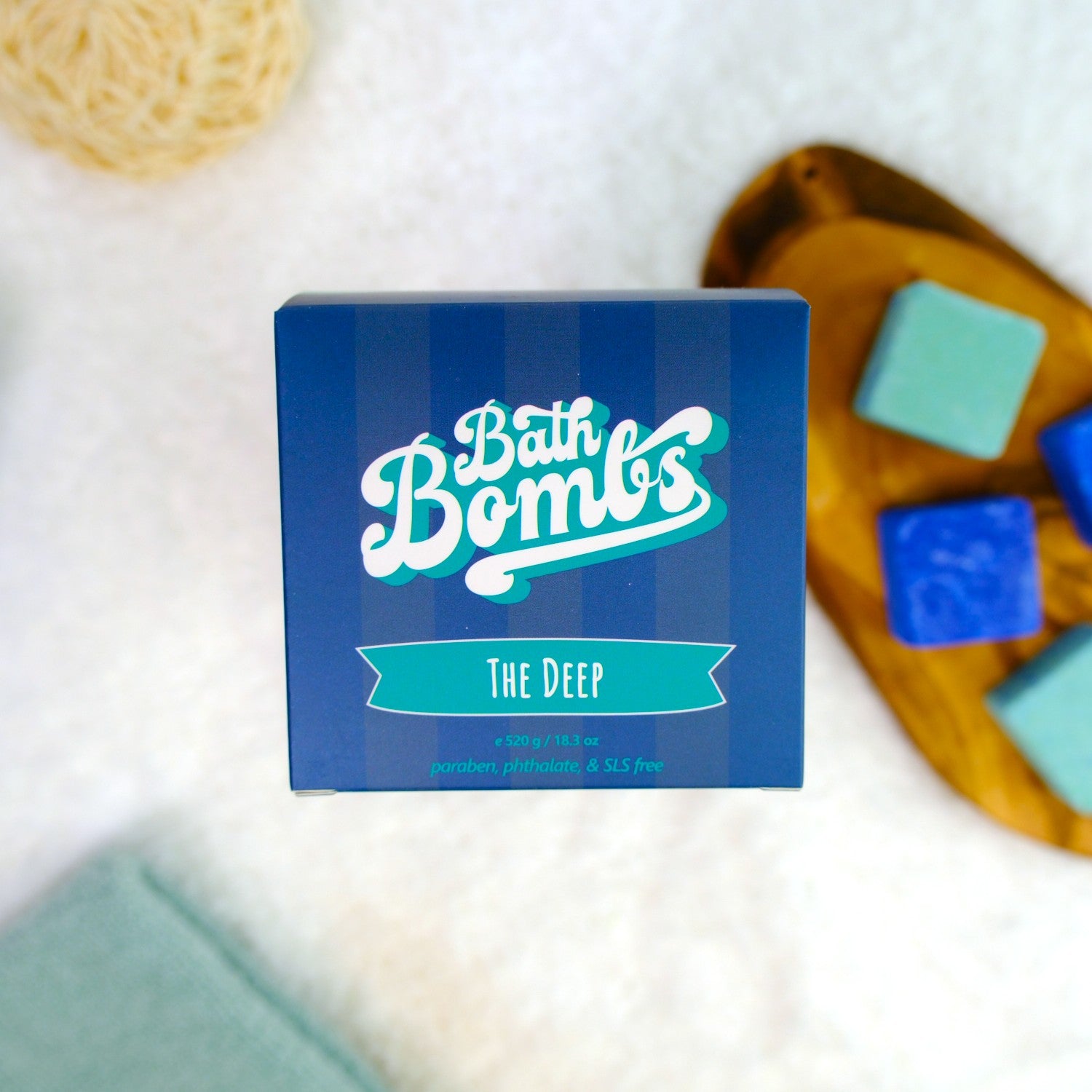 Box of Bath Bombs with bath bombs and a loofah on a white background