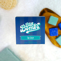 Box of Bath Bombs with bath bombs and a loofah on a white background